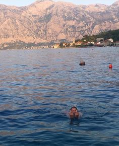 a person swimming in the water with mountains in the background