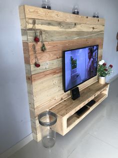 a flat screen tv sitting on top of a wooden shelf next to a glass vase