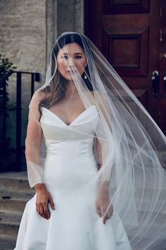 a woman in a white wedding dress is standing on steps with her veil over her face