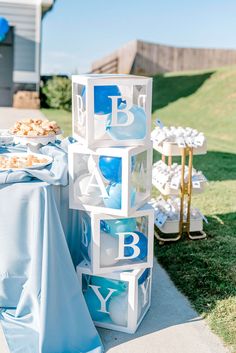 a blue and white baby shower is set up on the side of a table outside