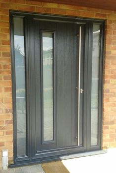 a black double door on a brick building with glass panels and sidelights in front of it