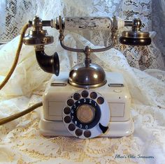 an old fashioned rotary telephone on a lace tablecloth