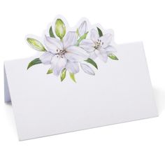 a card with white flowers on it and green leaves in the center, against a white background