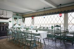 a dining room filled with lots of tables and chairs next to a fire place in front of a large window