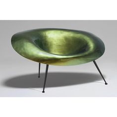 a green chair sitting on top of a metal frame with black legs and an oval shaped seat