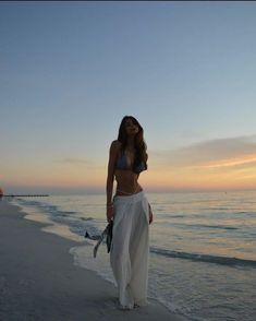 a woman standing on top of a beach next to the ocean