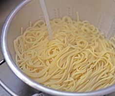 noodles being cooked in a strainer on the stove