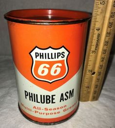 an orange and white phillips 66 oil can next to a measuring ruler on a table