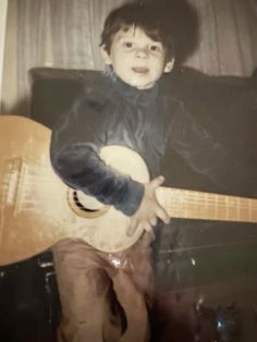 a young boy is playing an acoustic guitar