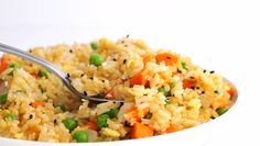 a white bowl filled with rice and veggies next to a fork in it