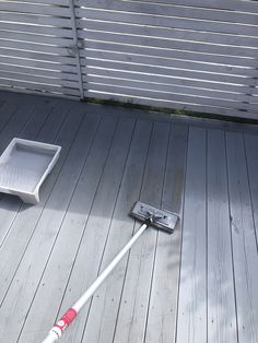 a mop laying on top of a wooden floor next to a white tray with a red handle