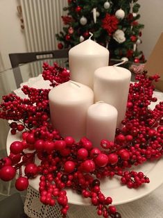 some candles are sitting on a plate with red berries