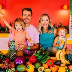 a man, woman and child standing in front of a table full of fruits and vegetables