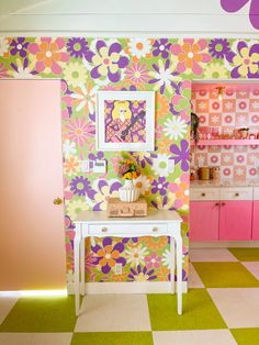 a room with flowers painted on the wall and pink cupboards in the back ground