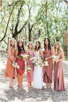 a group of women standing next to each other holding bouquets in their hands and smiling at the camera