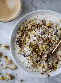 a bowl filled with oatmeal and nuts next to a cup of coffee