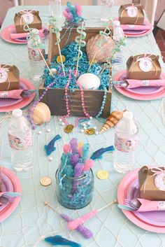 the table is set with pink, blue and gold decorations for an ocean themed birthday party