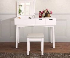 a white dressing table with a stool and mirror on top of it in front of a wall