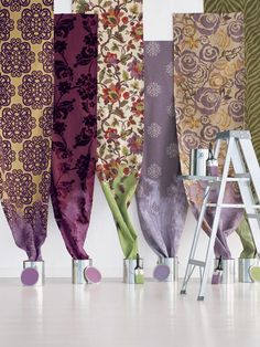 an array of different colored curtains hanging on a wall next to a stepladder