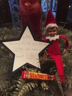 an elf is holding a star next to a candy bar