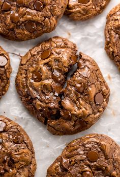 chocolate chip cookies on parchment paper with one broken in half and the other partially eaten