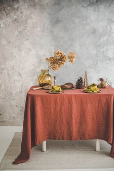 two vases with flowers are sitting on a red table cloth next to each other