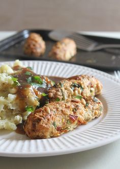 two meat patties covered in gravy and mashed potatoes on a plate