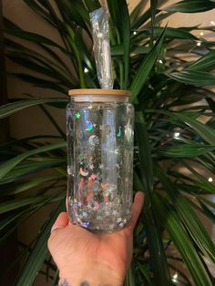 a hand holding up a jar filled with lots of confetti and glitters