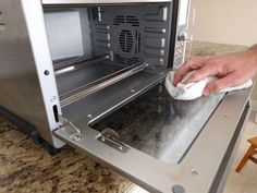 a person is cleaning an oven with a micro wave and a rag in their hand