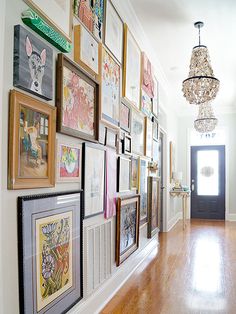 a hallway with pictures on the wall and a chandelier