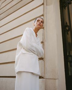 a woman leaning against the side of a building