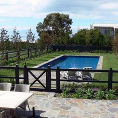 an empty swimming pool in the middle of a yard with chairs and tables around it