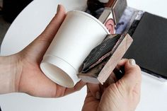 a person holding a coffee cup over a book on top of a white round table