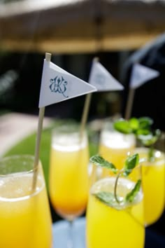 several glasses filled with orange juice and garnished with small flags