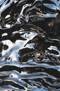 an abstract image of black and white water ripples on the surface with blue sky in the background