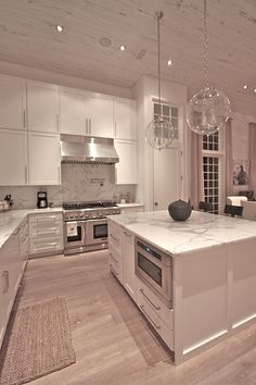 a large kitchen with marble counter tops and white cabinets