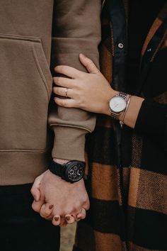 two people holding hands while standing next to each other with their arms wrapped around one another