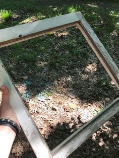 someone is holding up an old frame in the grass with their hand on top of it