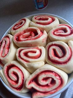 a bowl filled with rolled up dough on top of a white countertop next to a can of ketchup