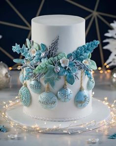 a white cake with blue frosting and decorations on the top, surrounded by lights