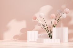 three white vases with pink flowers in them on a table next to a wall