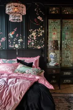 a bedroom with black walls and pink bedding, chandelier hanging from the ceiling