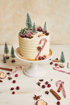 a christmas cake decorated with candy canes and candies on a white table surrounded by other holiday decorations