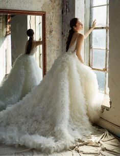 a woman in a wedding dress looking at herself in the mirror