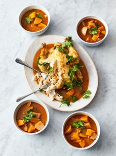 three bowls of soup with chicken, carrots and parsley garnish on the side