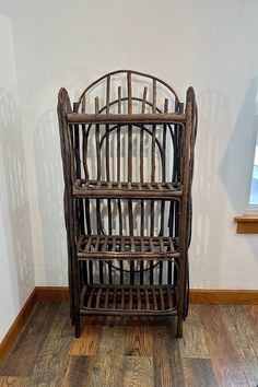 an old wooden rack sitting on top of a hard wood floor next to a window