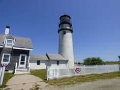 a light house sitting next to a white picket fence