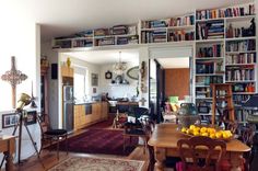 a room filled with lots of books and furniture next to a dining table in front of a doorway