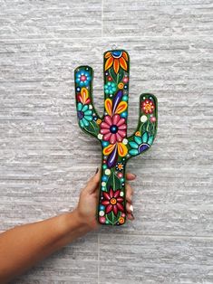 a hand is holding a colorful painted cactus