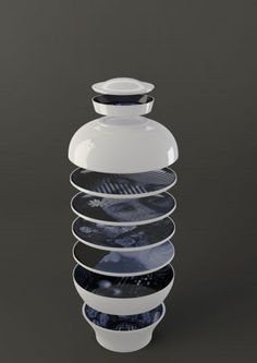 a white and black vase sitting on top of a gray table next to other plates